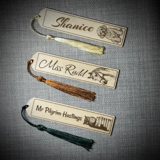 Pesonalised wooden bookmarks with images and names laser marked onto them and a decorative tassel.