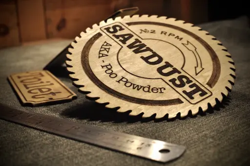 Custom laser cut and engraving on wood, in the shape of a circular saw blade with text.